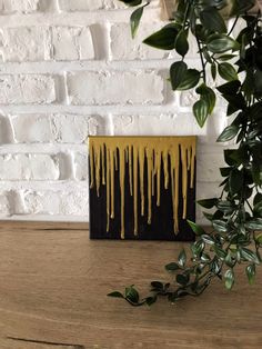 a wooden table topped with a plant next to a black and yellow box filled with liquid