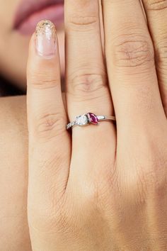 a close up of a person's hand with a ring on their finger and a woman's face in the background