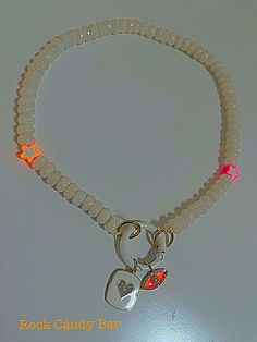 White gemstone beaded choker-style round white carabiner necklace with neon glowy star beads.  The round white carabiner holds a blingy squared enamel heart charm and a bright orange evil eye. Trendy White Charms Jewelry, Trendy White Jewelry With Charms, White Beaded Necklaces With Heart Charm As Gift, White Heart Charm Choker Necklace, White Jewelry With Star Charm And Round Beads, White Round Beads Jewelry With Heart Charm, White Heart Beads Choker Jewelry, White Jewelry With Heart Charm And Round Beads, White Choker Necklace With Heart Charm