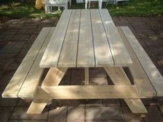 a wooden picnic table sitting on top of a brick patio