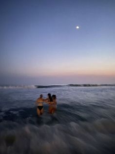 two women in the ocean hugging each other with a half moon above them and one woman holding her hand out