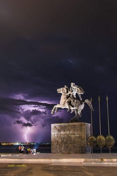 there is a statue that has lightning in the background