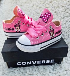 a pair of pink minnie mouse shoes on top of a black box with the word converse