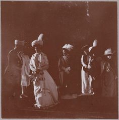 an old black and white photo of people dressed in fancy clothing with hats on their heads