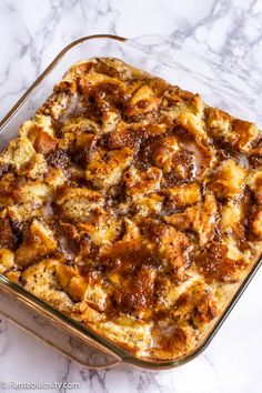 a casserole dish filled with bread and meat in a glass baking dish on a marble countertop