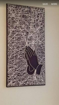 a wall hanging on the side of a building with a praying hand painted on it