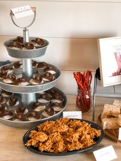 three tiered trays filled with pastries next to other food items on a table