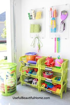 there is a green shelf with toys on it and two bins in front of the wall