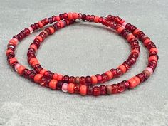 This red glass beaded necklace is made of size 6/0 Czech glass seed beads in a variety of red tones. It can be made as a bracelet, anklet, or necklace - or order it in a stretch option that's long enough for wrapping and you can get a variety of styles from this piece! Note that stretch options will often be finished with a metal bead to secure the knot - the bead will be in the accent metal of your choice if the other beads do not have a sufficient hole size to secure and hide a knot properly. Red Beaded Bracelet With 108 Beads For Festival, Red Czech Glass Bracelets With Colorful Beads, Handmade Red Beaded Bracelets For Beach, Red Czech Glass Beaded Bracelets With Colorful Beads, Adjustable Red Czech Glass Beads, Handmade Red Czech Glass Beaded Bracelets, Red Bohemian Beaded Bracelet, Red Beaded Bracelets With Spacer Beads For Festival, Festival Red Beaded Bracelets With Spacer Beads