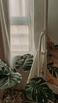 a white bag sitting on top of a wooden table next to a mirror and plant