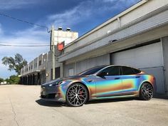 a silver car parked in front of a building with an orange and blue metallic paint job