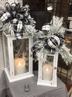 two white lanterns with black and white bows on them sitting on top of a table