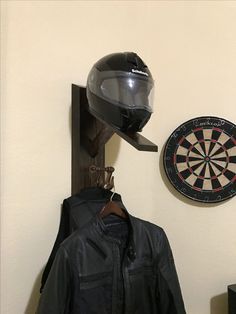 a helmet and jacket hang on the wall next to a dart