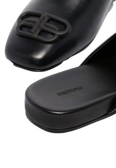 These black Balenciaga BB logo leather slipper shoes feature a square toe, slip-on design, flat sole and BB logo plaque.Calfskin leather with leather soleRubber tap heelMatte black-tone BB logo detail Composition: Leather 100%Lining Composition: Leather 100%Sole Composition: Leather 100% Fits true to sizeMade in Italy Classic Black Mules With Textured Sole, Leather Mules With Branded Heel For Business, Black Square-toe Calf Leather Loafers, Black Square Toe Calf Leather Loafers, Designer Square Toe Mules With Branded Insole, Designer Mules With Branded Insole And Square Toe, Designer Black Slip-ons With Rubber Sole, Designer Leather Mules For Business, Black Square Toe Mules