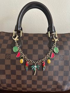 a brown and black purse with charms on it's chain hanging from the handle