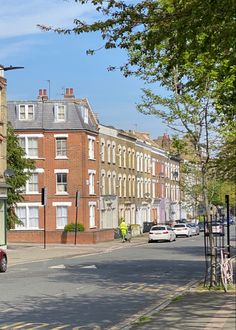 an empty street with cars parked on the side and buildings in the backround