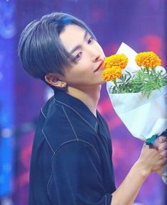 a young man holding flowers in front of his face