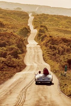 an old car driving down a dirt road