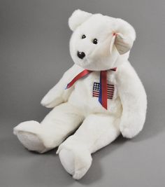 a white teddy bear with an american flag ribbon around its neck