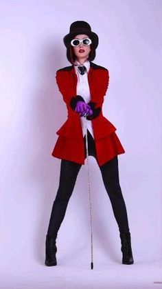 a woman in a red coat and black hat is holding a purple ball on a stick