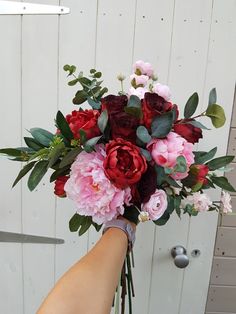 a person holding a bouquet of flowers in their hand on the side of a building