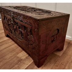 an old wooden chest with carvings on the front and sides sitting on a hard wood floor