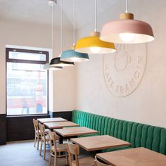 several tables and chairs are lined up against the wall in a restaurant with hanging lights above them