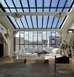 a living room filled with white furniture and lots of windows overlooking the cityscape