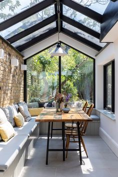 a room with a table, couches and windows on the outside wall is lit by a large skylight