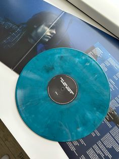 a blue vinyl record sitting on top of a white table next to an album cover