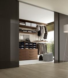 an open closet with clothes and suitcases on the floor, next to a lamp