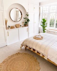 a bedroom with a bed, dresser and round mirror in the corner on the wall