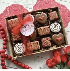 valentine's day chocolates in a box on a table with red roses and doily