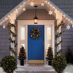 a blue front door decorated for christmas with lights and wreaths on the steps leading up to it