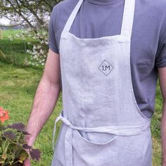 a man wearing an apron and holding a potted plant in his hand with the letter m on it