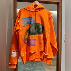 an orange hoodie hanging on a mirror