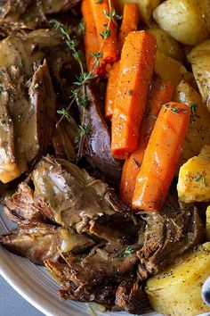 a white plate topped with roast, potatoes and carrots