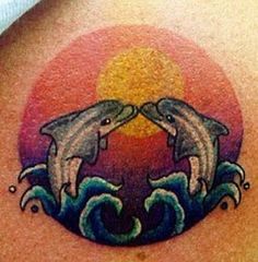 two dolphins on the back of a woman's shoulder