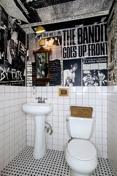 a white toilet sitting next to a bathroom sink under a wall covered in black and white pictures