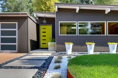 a house with two garages and three plants in the front yard