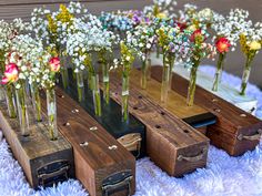 several wooden boxes with flowers in them sitting on a white blanket next to each other