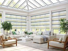 a living room filled with lots of furniture and windows covered in blind shades over the windows