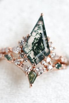 a green and white diamond ring sitting on top of a table next to a napkin