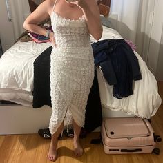 a woman in a white dress taking a selfie with her cell phone and suitcase