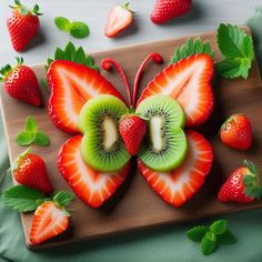 sliced kiwi, strawberries and strawberrys on a cutting board with mint leaves