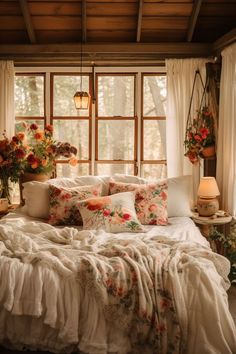 a bed sitting in a bedroom next to a window filled with lots of pillows and blankets