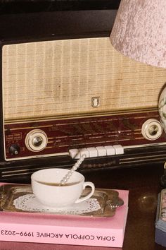 an old radio sitting on top of a table next to a cup and saucer