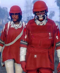 two people wearing red uniforms and helmets walking in the snow with their hands on their hips