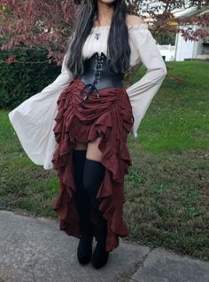 a woman wearing a pirate costume standing in front of a tree with her hands on her hips