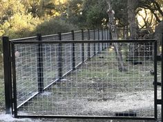 a gate that is in the middle of a field with grass and trees behind it